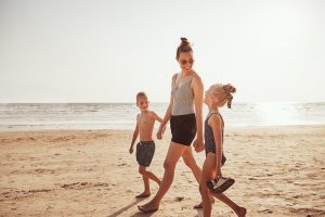 A mom and her young children walk along the beach in Pacific Beach, California