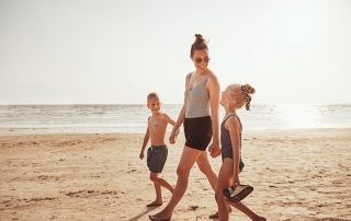 A mom and her young children walk along the beach in Pacific Beach, California